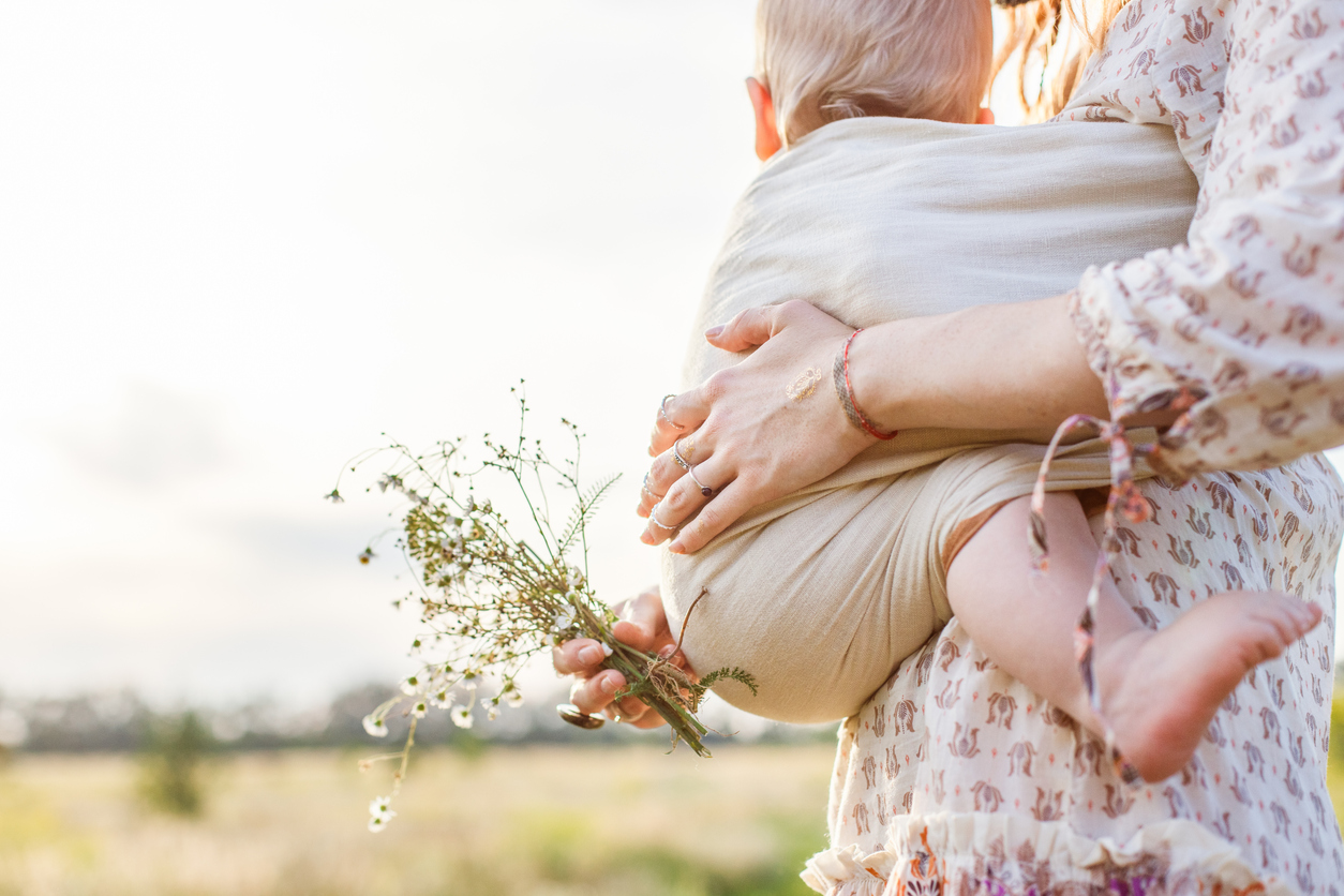 Mutter mit Blumenstrauß und Baby im Tagebuch am Körper